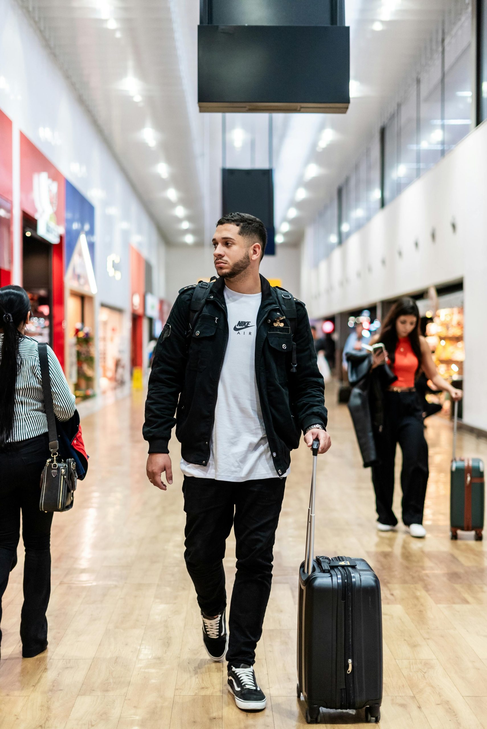 Traveler walking through airport terminal with rolling suitcase for business trip