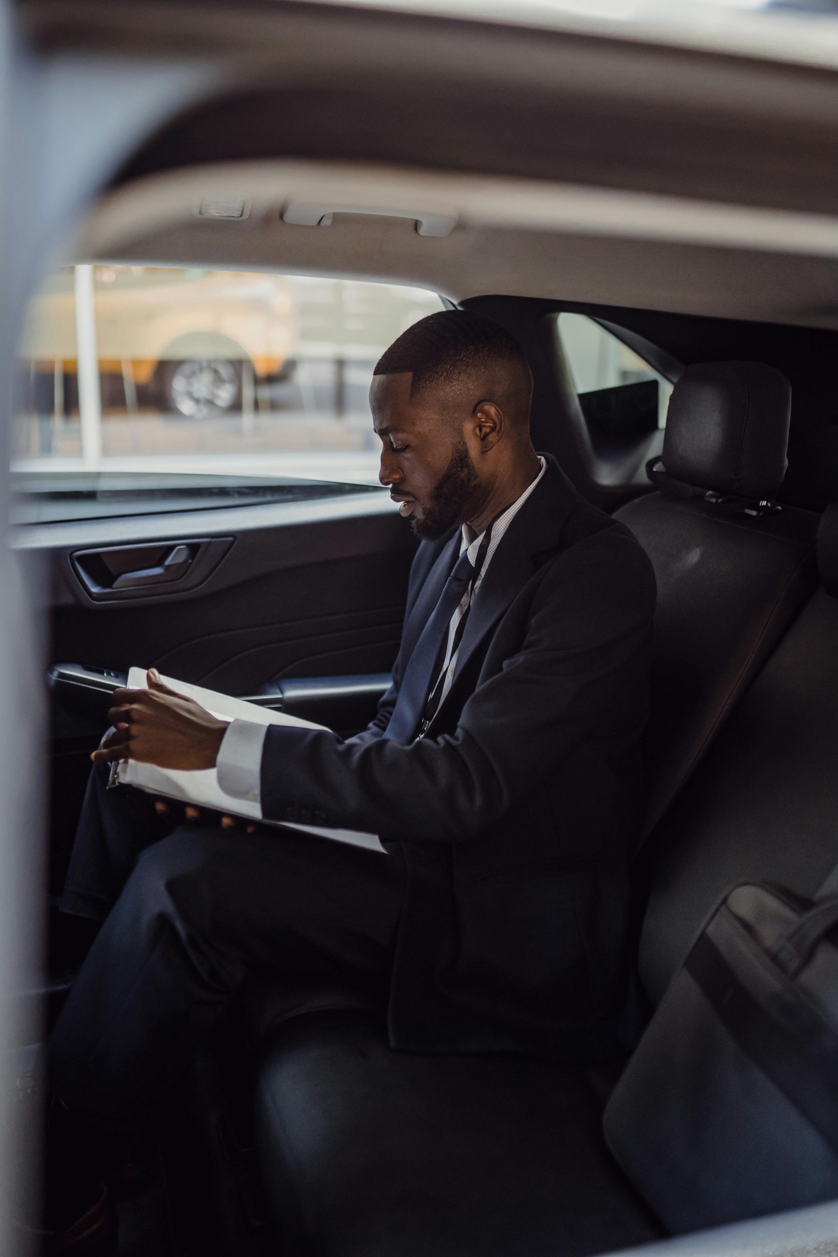 Business executive reading documents inside luxury car with premium leather interior